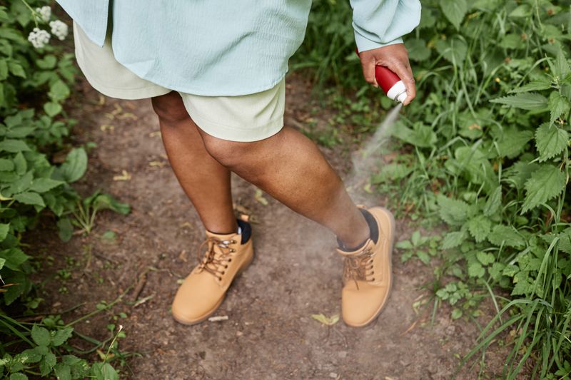 A person wearing shorts and sneakers gardening outdoors.