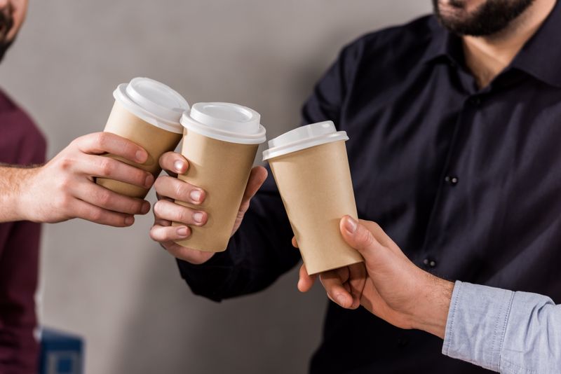 A cup, disposable cup, finger, hand, person.