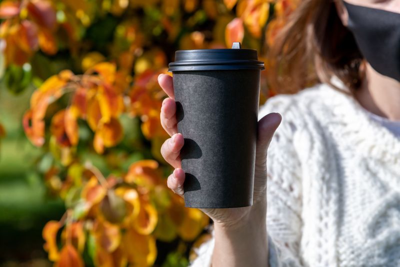 A person holding a disposable coffee cup for photography.