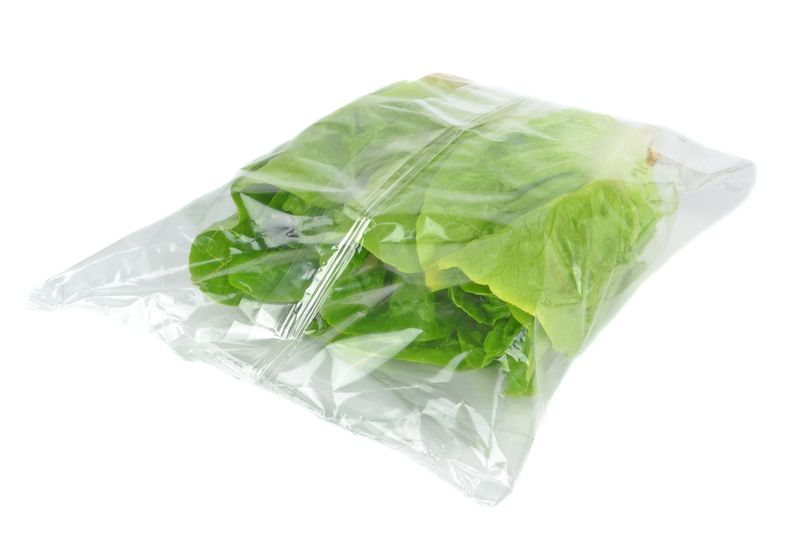 A plastic bag containing food and produce, including lettuce.