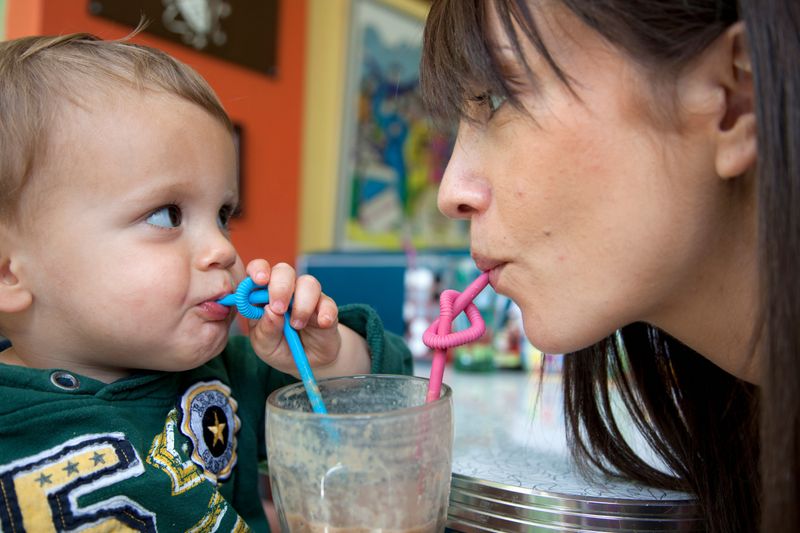 A baby holding a juice smoothie with a spoon.