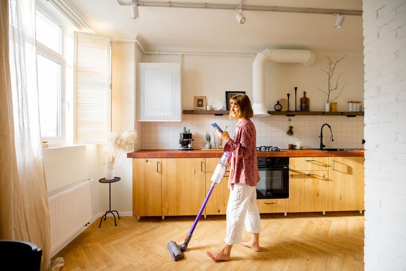 A child cleaning hardwood floors in a kitchen.