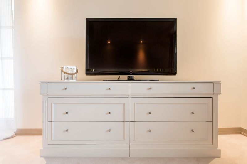 A computer monitor and TV on a cabinet in a room.