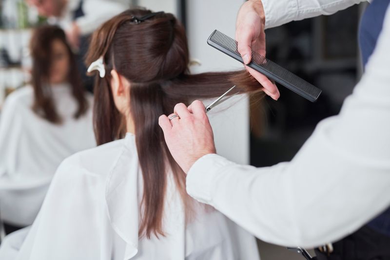 A hairdresser cutting a woman's hair with scissors.