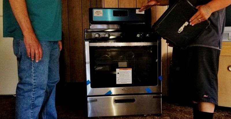 A person wearing jeans and a ring using a microwave.