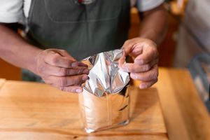 A person holding a sheet of aluminum foil.
