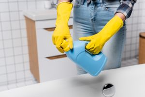 A person cleaning clothing indoors with gloves.