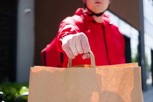A person holding a handbag with their hand.
