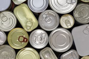 A stack of aluminum and tin cans with food on a plate.