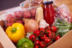 A box of food including ketchup, produce, bell pepper.
