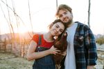 A smiling man and woman wearing pants and a necklace.